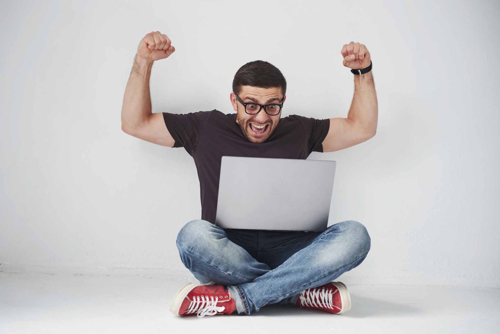 young-caucasian-man-sitting-over-white-brick-wall-using-computer-laptop-scaled